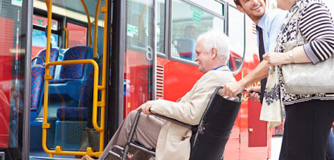 Driver Helping Elderly Senior Couple Board Public Bus Via Wheelchair Ramp